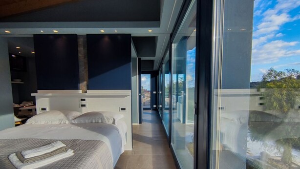 A modern hotel room with a large bed, a walk-in closet, and a glass wall offering a view of the outdoors. - [Luxury & Relaxation] Private Pool with View (Civitanova MARCHE)