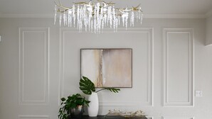 A modern interior with a chandelier, a console table with a plant, and a large abstract painting on the wall. - Embrace Tranquility: A modern retreat home where serenity meets style (Elizabeth City)
