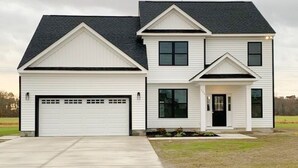A two-story house with a garage, a covered front porch, and a well-maintained lawn. - Embrace Tranquility: A modern retreat home where serenity meets style (Elizabeth City)