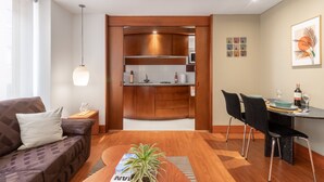 Un salon moderne comprenant un canapé, une table à manger avec des chaises, un coin cuisine et une plante en pot.