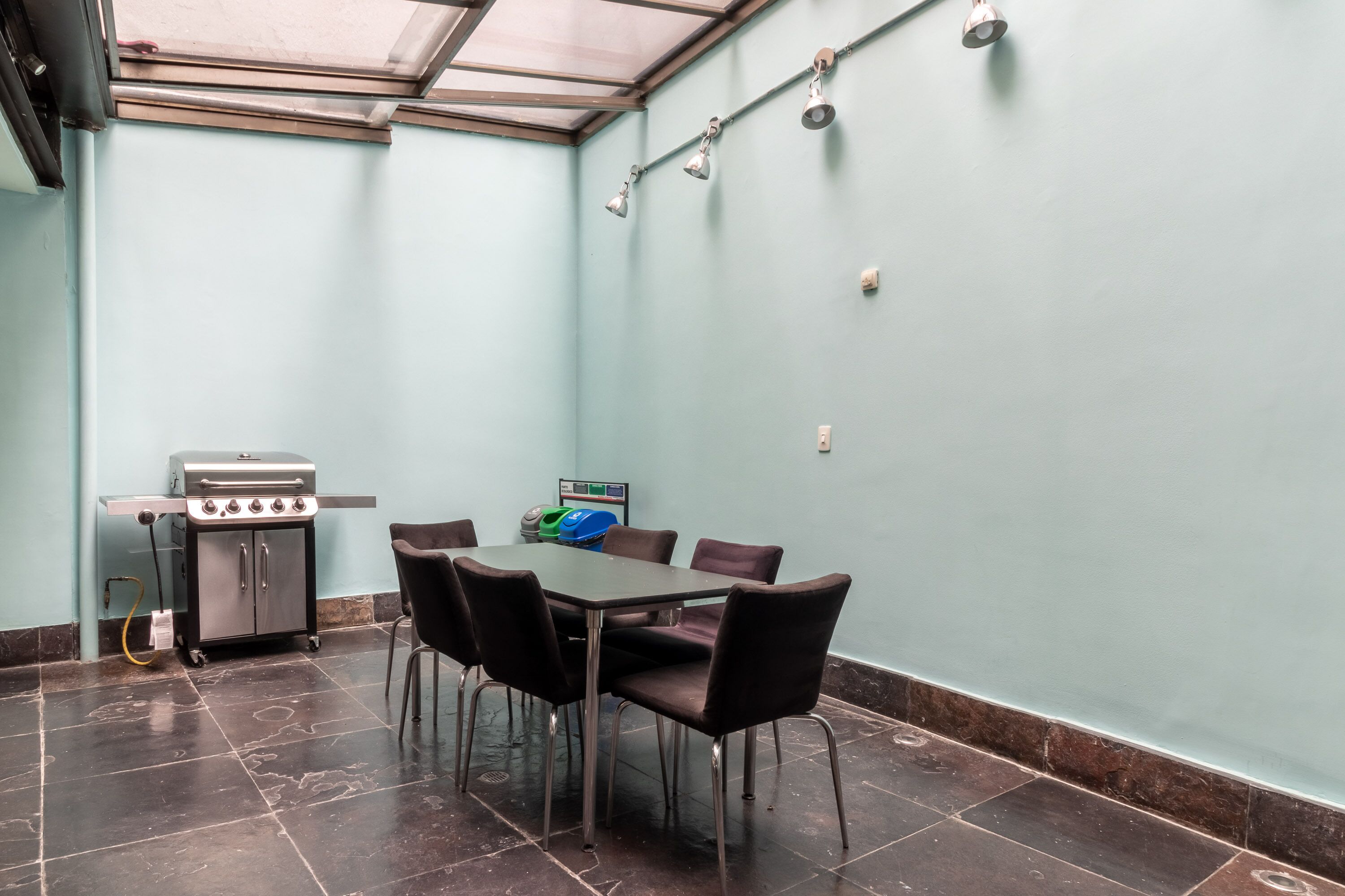 Una stanza con tavolo e sedie, un barbecue e una ventola a soffitto.