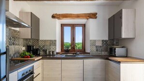 Une cuisine compacte dotée d’un îlot central, d’un four encastré, d’un four à micro-ondes et d’une fenêtre située au-dessus de l’évier.
