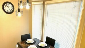 Uma área de refeições com mesa de mármore, cadeiras pretas e um relógio na parede.