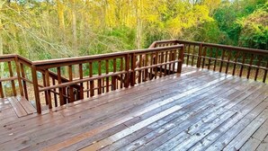 Um deck de madeira com guarda-corpo, rodeado por árvores.