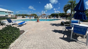 A pool area with hexagonal tiles, lounge chairs, and umbrellas. - The Green Grouper, oversized beach villa. (Central Abaco , Treasure Cay)