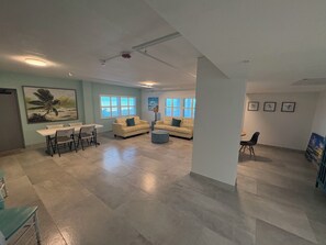 Un salón amplio con comedor, dos sofás, una mesa de centro y un cuadro grande en la pared.