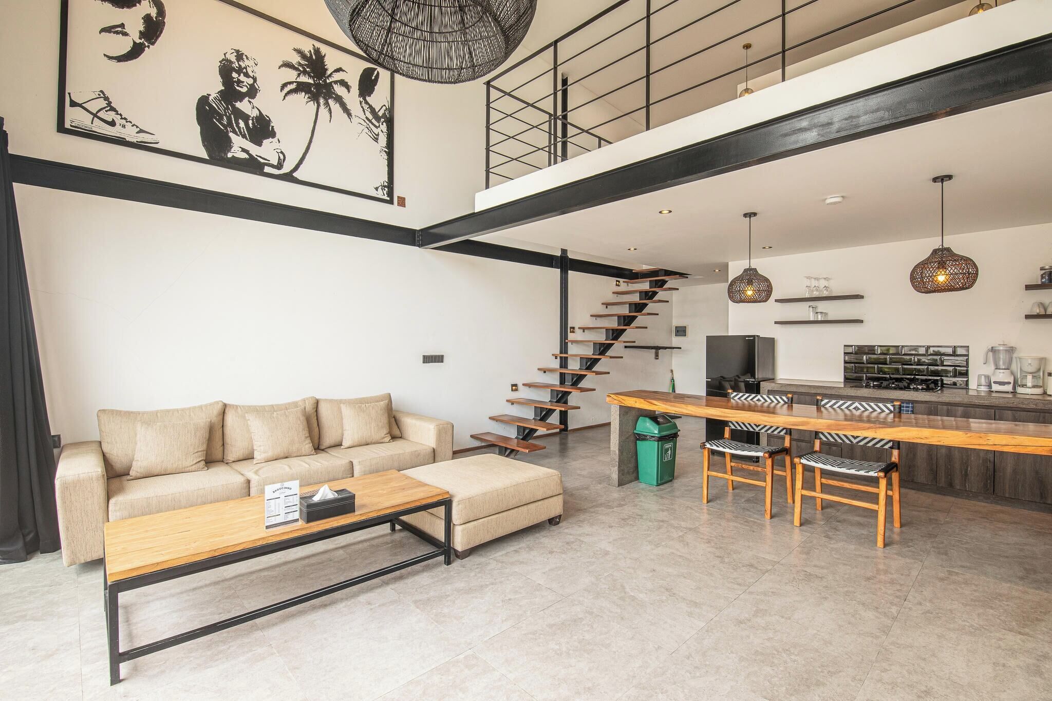 A spacious living area with a sofa, coffee table, and a staircase leading to a kitchen area.