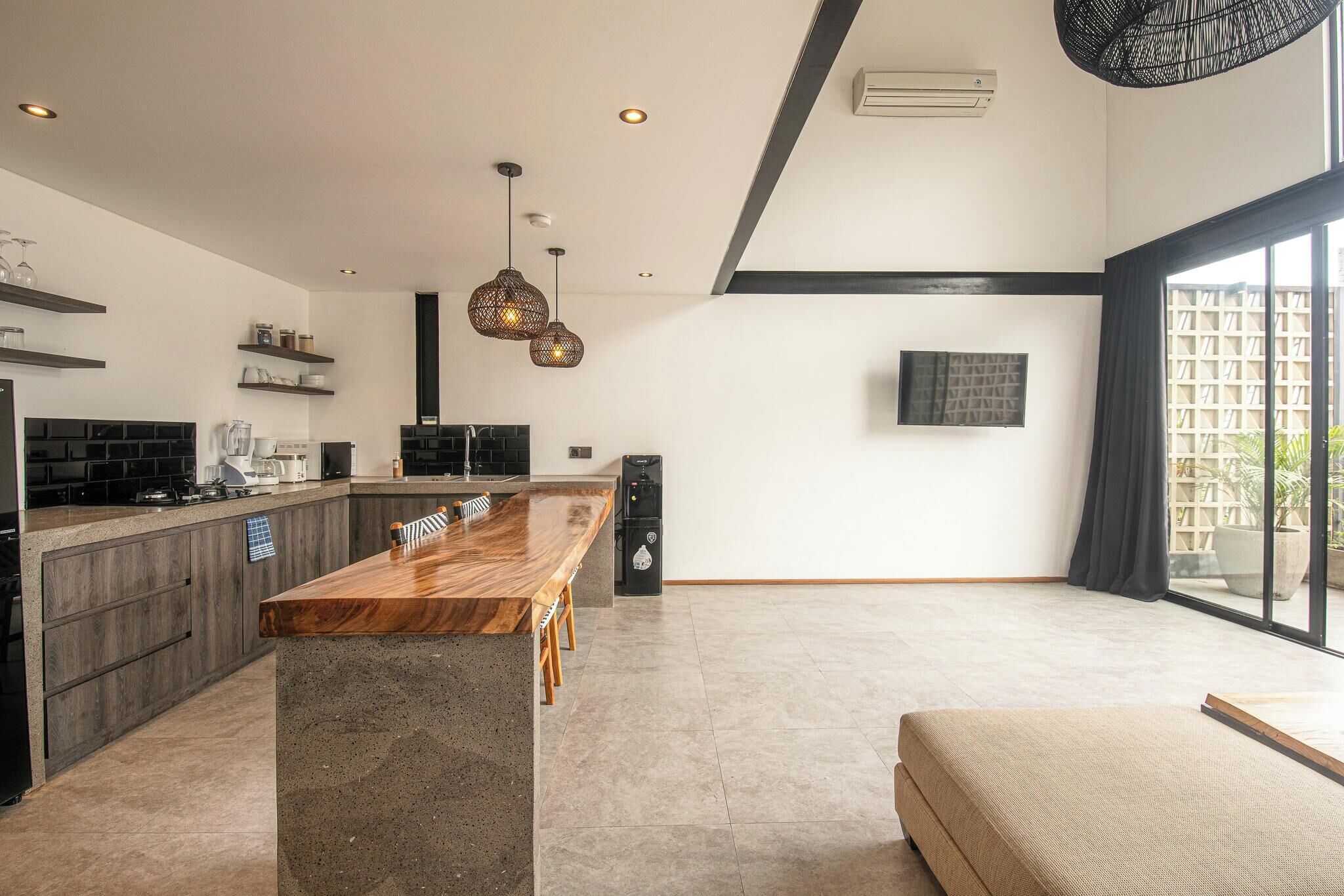 A modern kitchen with a wooden countertop, built-in cabinets, and pendant lighting.