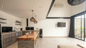 Una cocina moderna con encimera de madera, armarios empotrados e iluminación colgante.