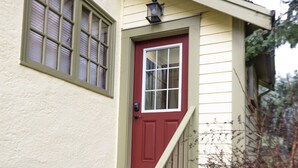 A house with a red door, a small porch, and a wooden staircase.