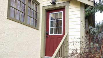 A house with a red door, a small porch, and a wooden staircase.