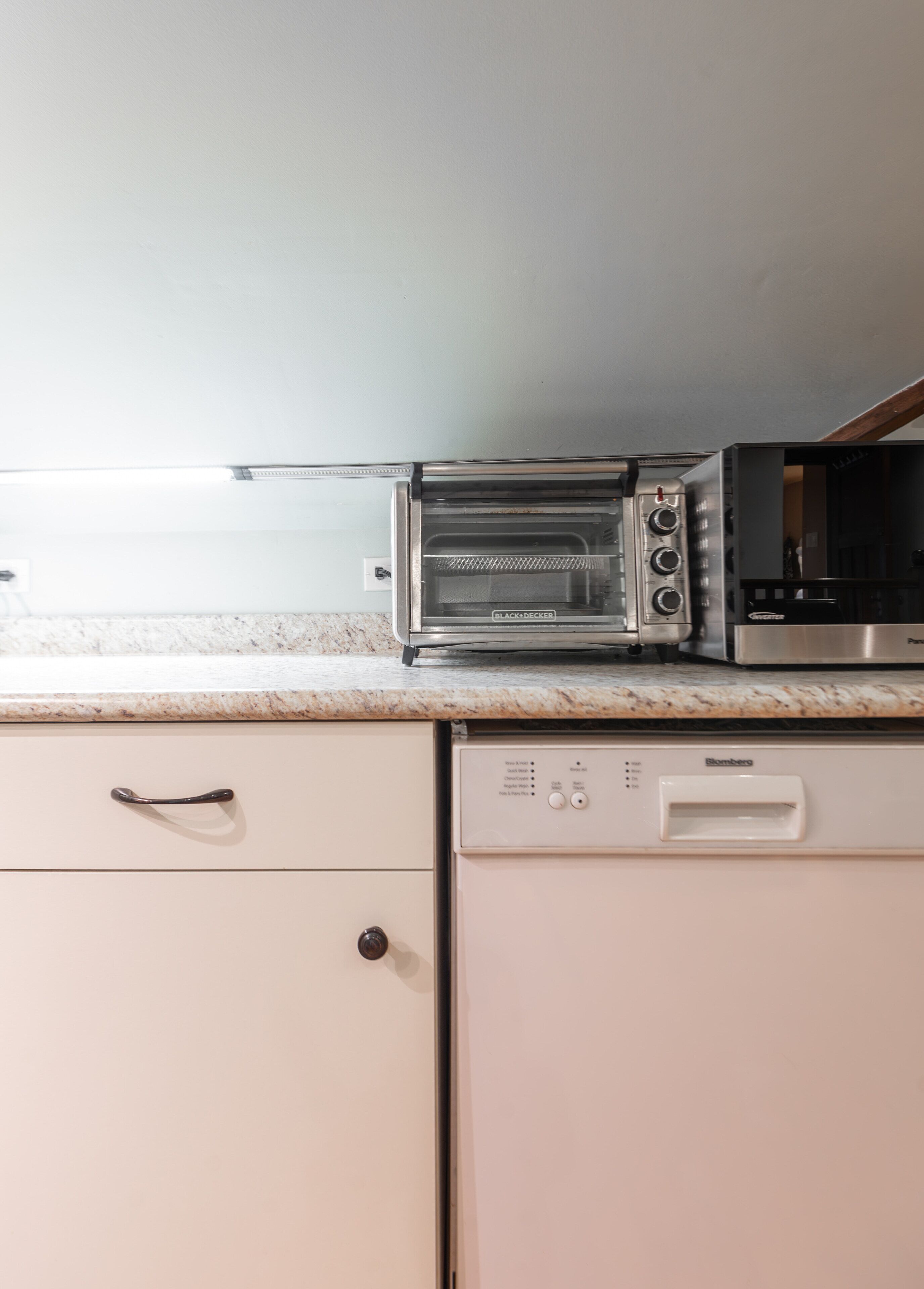 Una cocina equipada con horno tostador, microondas y lavavajillas.
