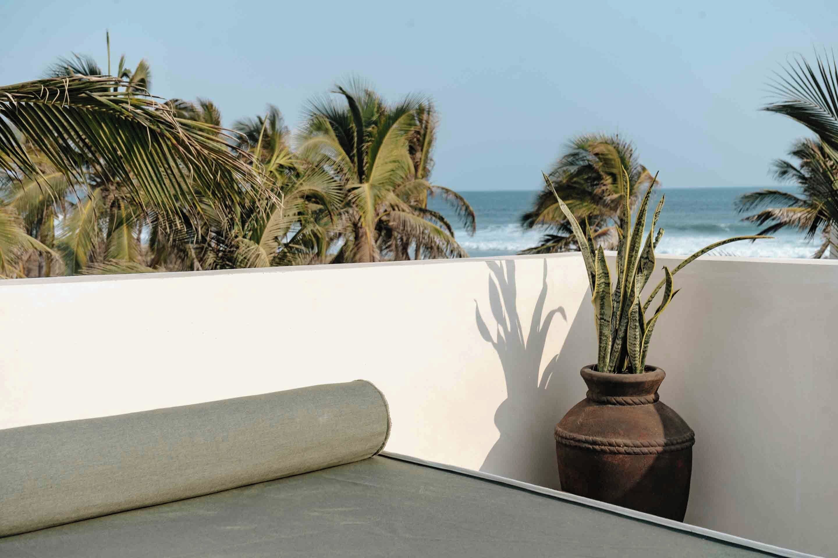 A balcony with a view of the ocean and palm trees.