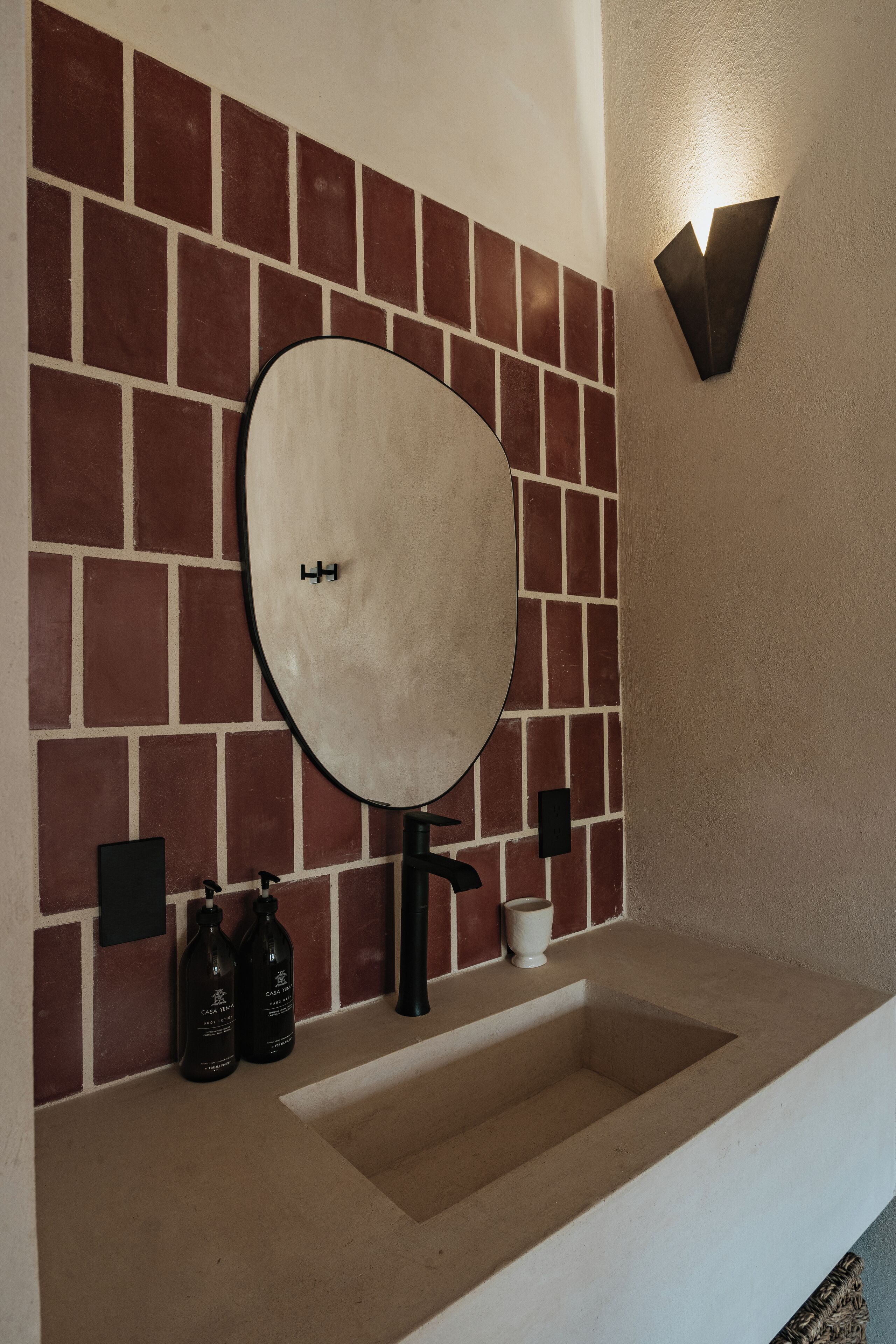 Un baño con un espejo grande, un lavabo y una lámpara de pared.