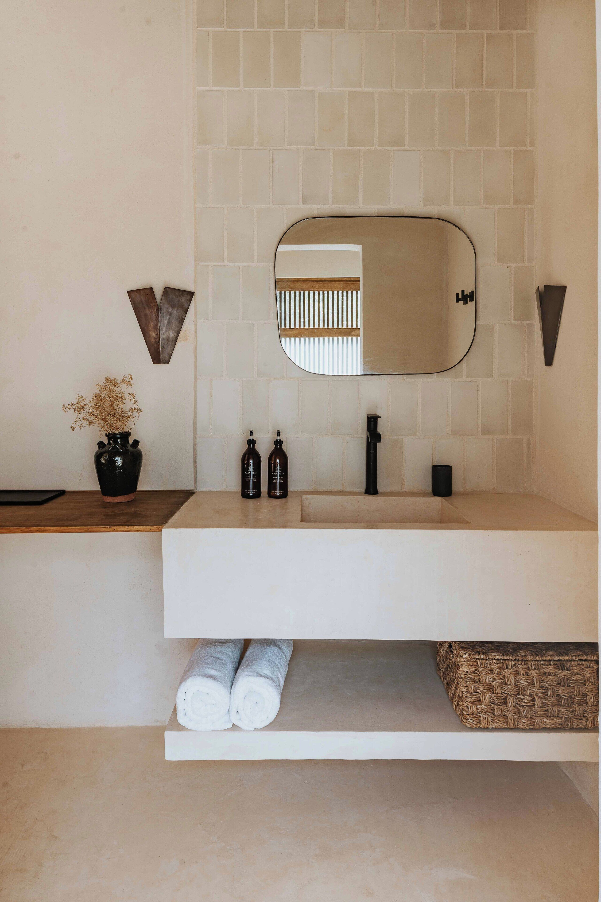 A bathroom with a white sink, a mirror, and a towel rack.
