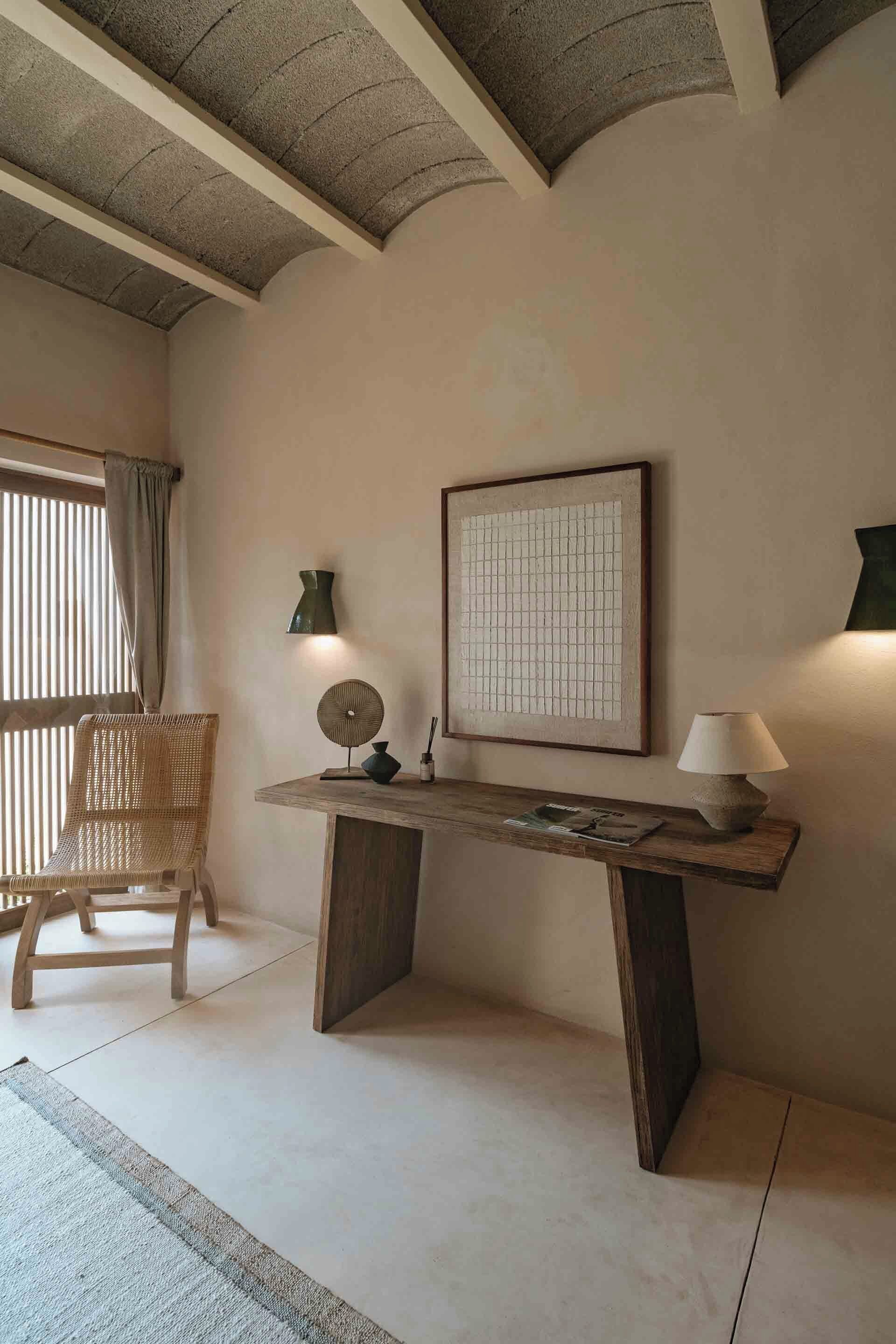 A room with a wooden desk, a chair, a framed picture, and a lamp.