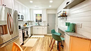 Une cuisine moderne avec des armoires blanches, des appareils en acier inoxydable et un plancher en bois.
