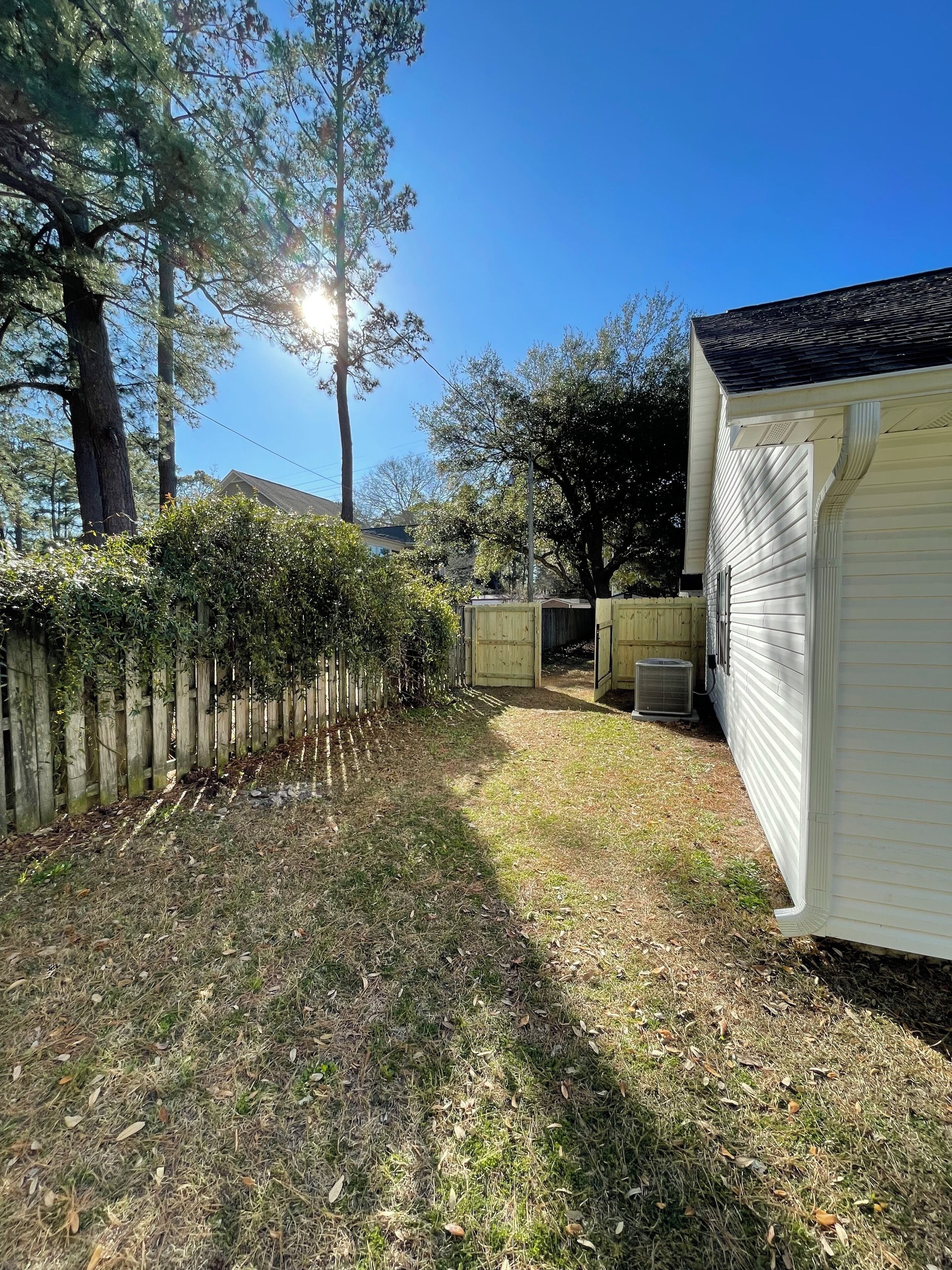 A residential area with a wooden fence, a grassy yard, and a white mobile home.