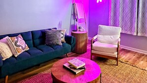 Un salon moderne avec un canapé bleu, une table basse ronde en bois et un fauteuil blanc.