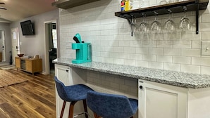 Une cuisine moderne avec des carreaux de céramique blancs disposés en motif métro, un comptoir en granit et deux tabourets de bar.