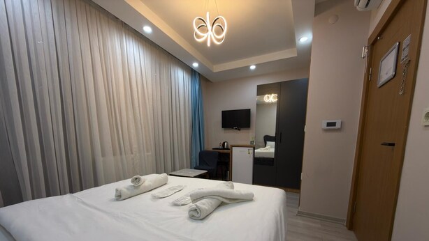Une chambre d’hôtel avec un grand lit, un bureau, une chaise, une télévision et une armoire.