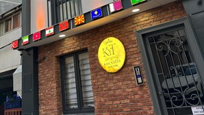 Il s’agit d’un hôtel à l’architecture moderne, doté de nombreux balcons et d’une enseigne indiquant qu’il propose des suites. Des drapeaux de différents pays sont accrochés à la façade de l’immeuble.