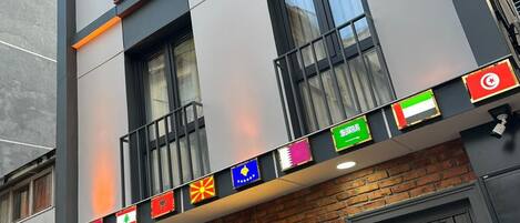 Il s’agit d’un hôtel à l’architecture moderne, doté de nombreux balcons et d’une enseigne indiquant qu’il propose des suites. Des drapeaux de différents pays sont accrochés à la façade de l’immeuble.
