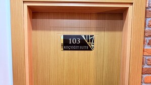 Une porte en bois avec une plaque indiquant le numéro de la chambre, 103, et l’inscription « Koçyiğit Suite ».