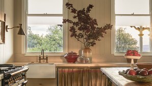 Una cocina con pisos de madera, estufa, pileta y ventana con vista a follaje.