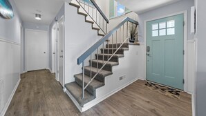 Una escalera con barandilla de metal, una puerta con ventana y un suelo de madera.