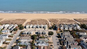 Vista aérea de una zona residencial costera con casas, una playa y un cielo despejado.