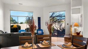 A dining area with a wooden table set for four, two vases with dried plants, and a blue chair in the background. - Golf & Pickleball at Casa de Cielos (Sedona)