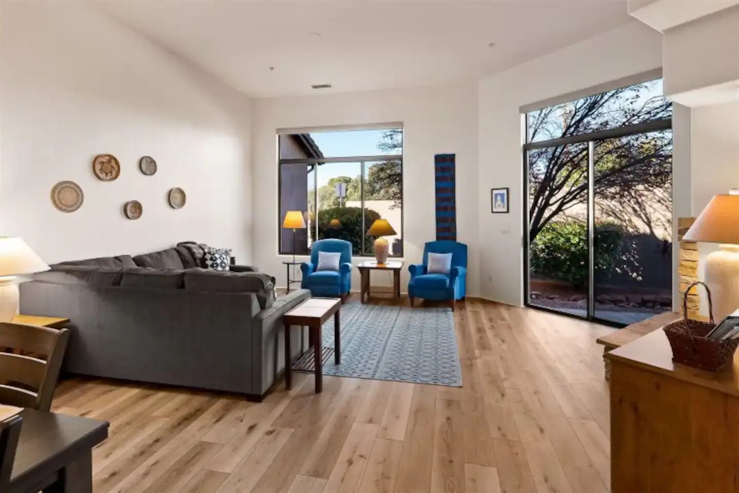 Un salon moderne avec un canapé gris, deux fauteuils bleus, une table basse et une cheminée.