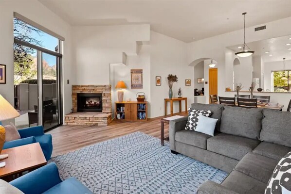 Un salón amplio con chimenea, un comedor y un gran ventanal.