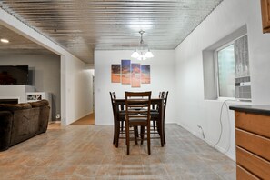 Un comedor con una mesa y sillas, un televisor al fondo y obras de arte en la pared.