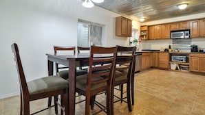 Una cocina con armarios de madera, una mesa de comedor con sillas y un microondas.