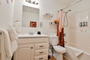 Un baño moderno con un tocador blanco, un inodoro, una ducha con puerta de cristal y un espejo sobre el lavamanos.