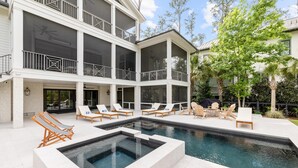 Une maison moderne dotée d’une piscine, de plusieurs balcons et d’un espace salon extérieur.