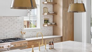 Une cuisine moderne dotée d’un grand îlot central, de meubles en bois et de luminaires suspendus.