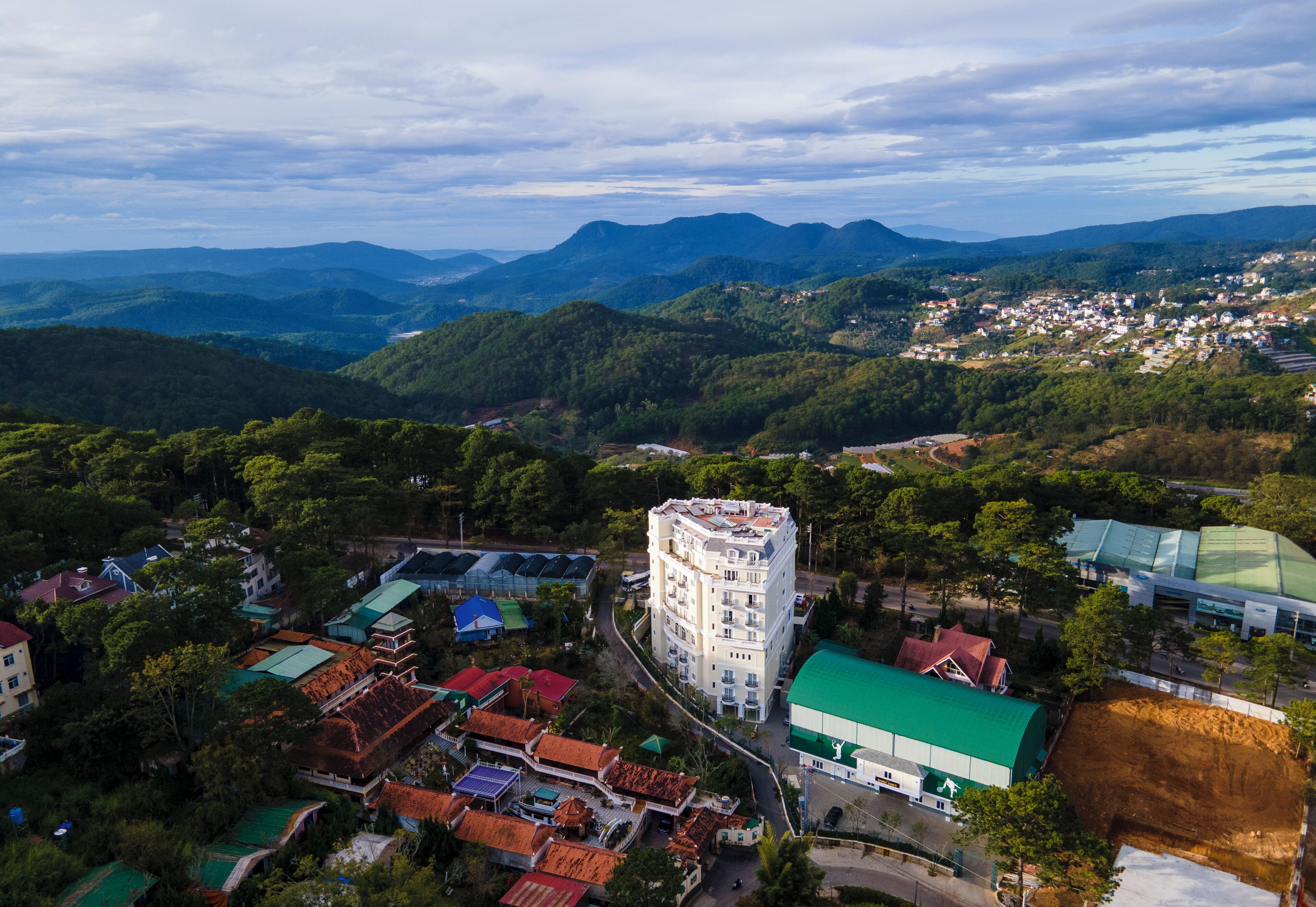 An aerial view of a town with a prominent white building surrounded by residential houses and greenery.
