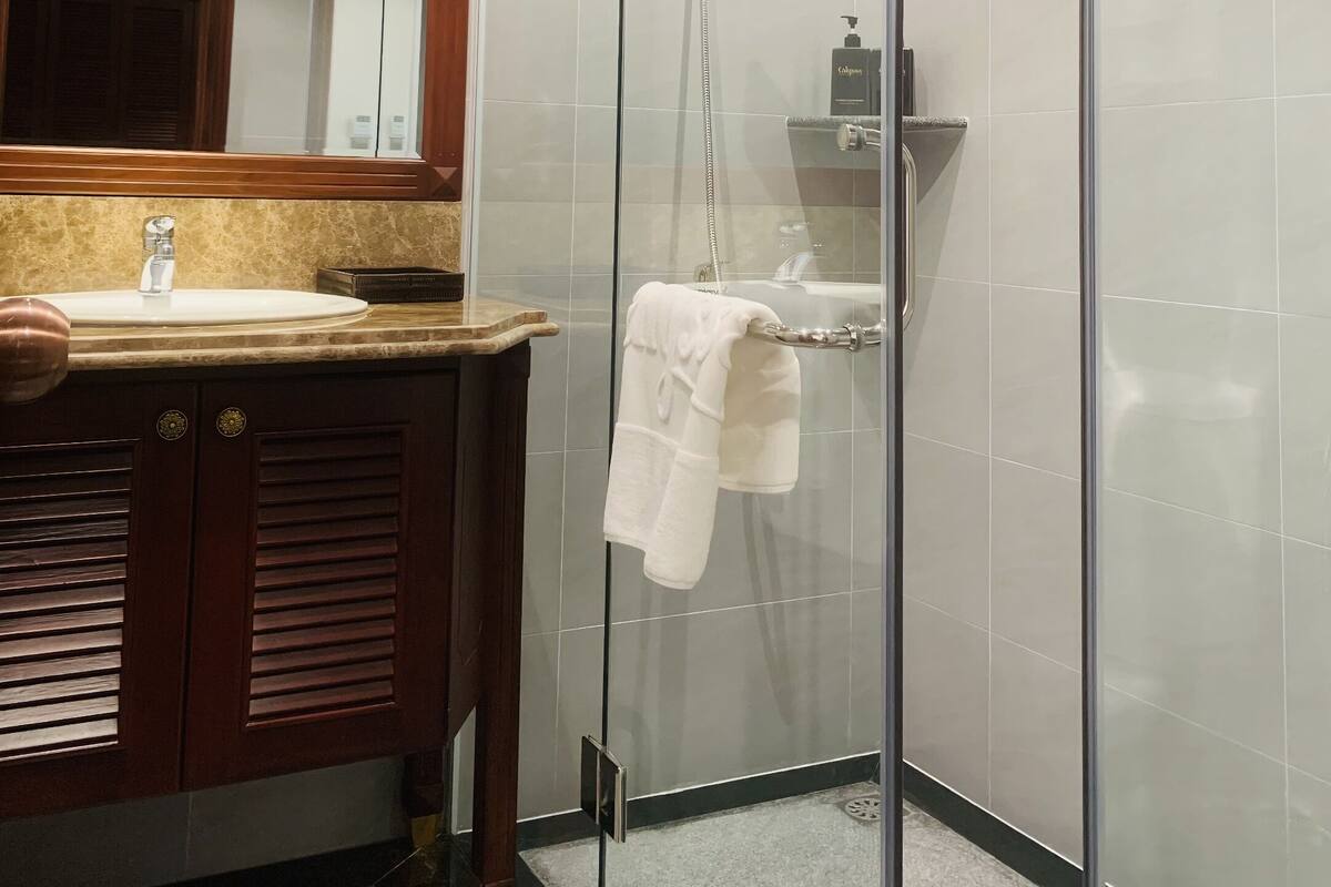 A modern bathroom with a glass-enclosed shower, a vanity with a sink, and a mirror.