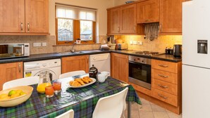 A kitchen with wooden cabinets, a microwave, a toaster, and a water dispenser. - Culduthel by Interhome (Aviemore)
