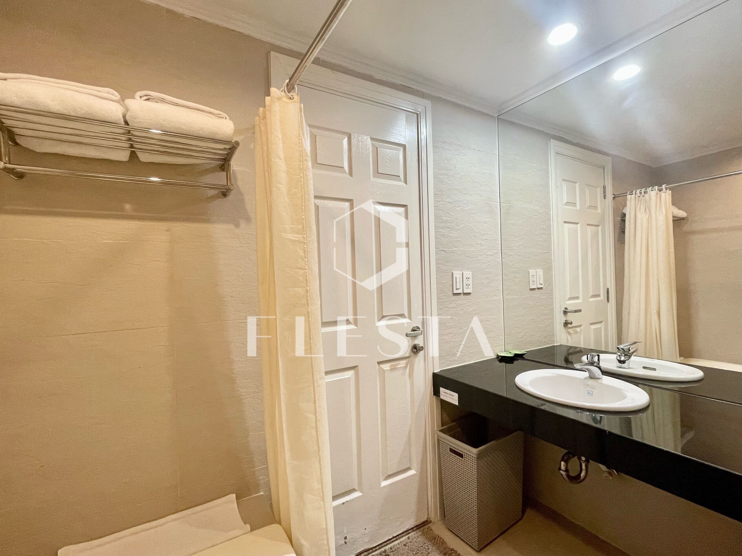 A modern bathroom with a white door, a black countertop, and a mirror.