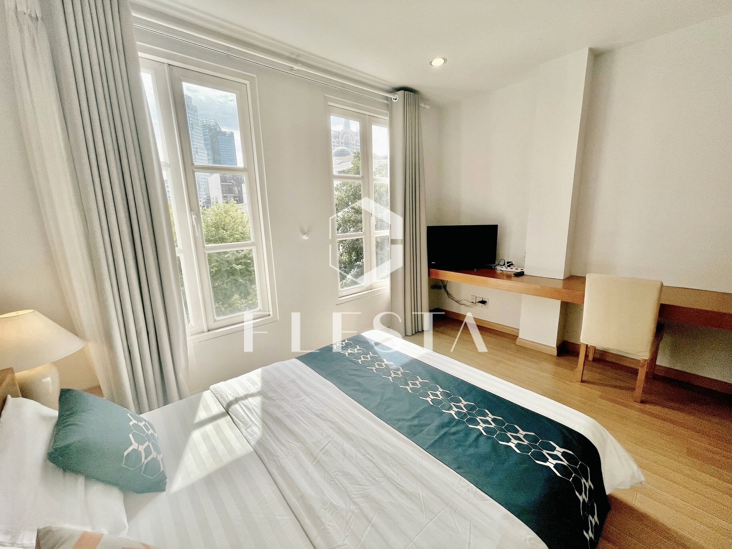 Une chambre d’hôtel avec un lit, un bureau, une télévision et une fenêtre avec des rideaux.