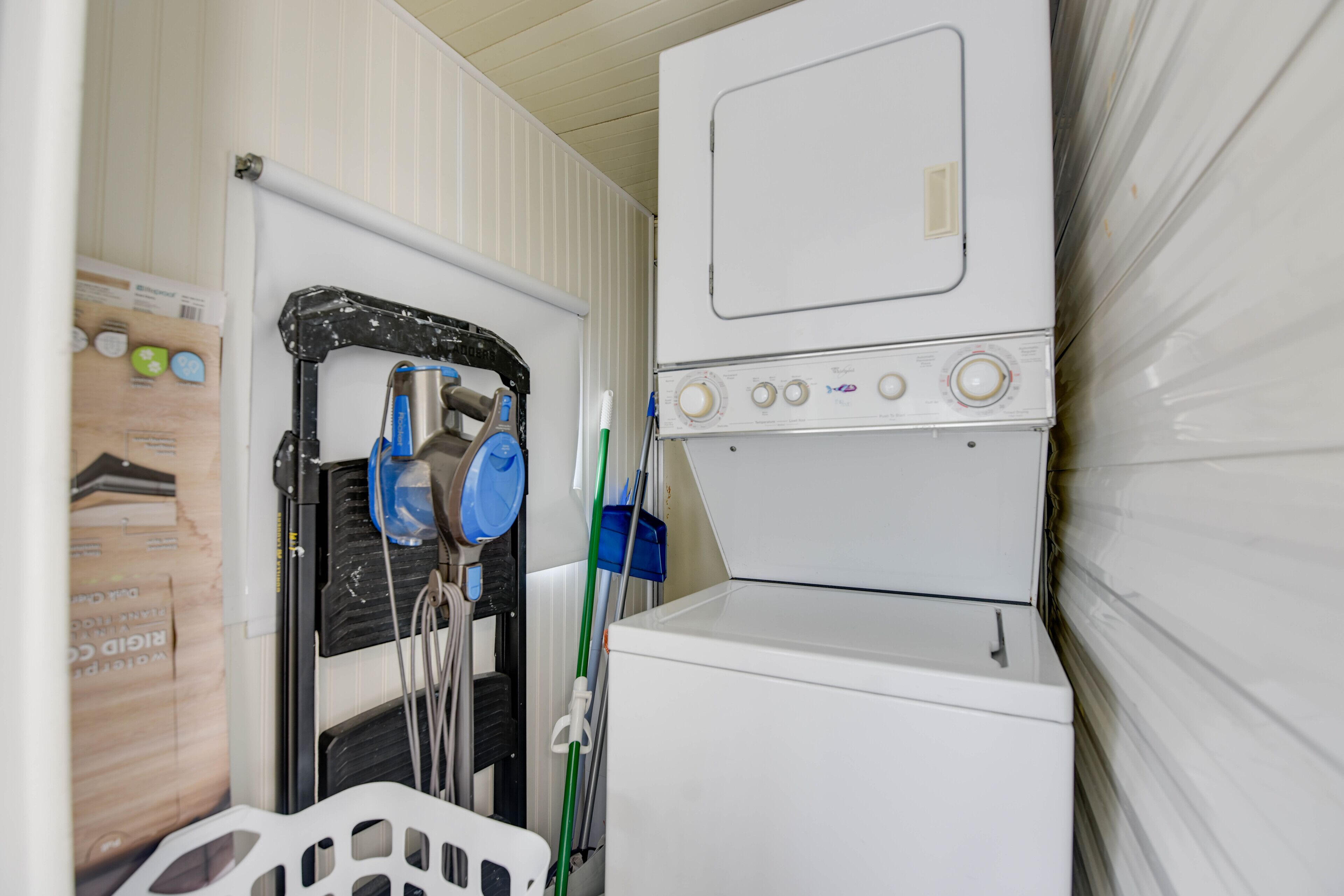 A laundry area with a washing machine and dryer, a drying rack, and a basket.