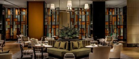A modern lounge area with seating arrangements, a central plant, and decorative lighting.
