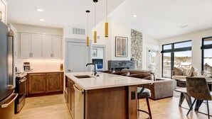A modern kitchen with a central island, wooden cabinets, and pendant lighting.