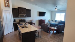 A modern kitchen with dark wood cabinets, a granite countertop, and a built-in microwave.