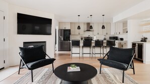 A modern living room with a black round coffee table, two black armchairs, and a large flat-screen TV mounted on the wall. - Old Town Gem by Porter | Dog-Friendly Home w/Heated Pool and Arcade Games (Scottsdale)