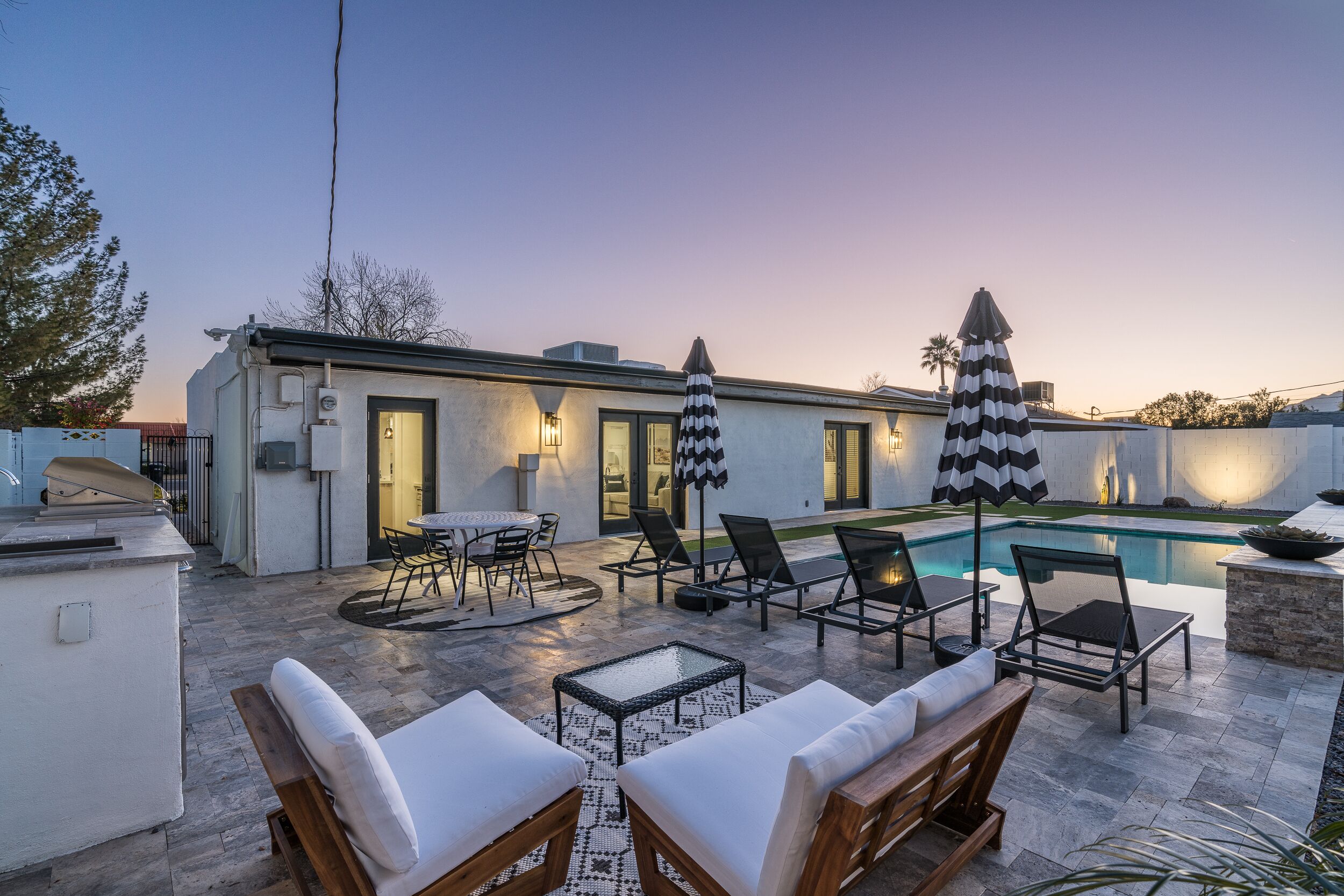 A modern outdoor patio with lounge chairs, a pool, and a dining area.